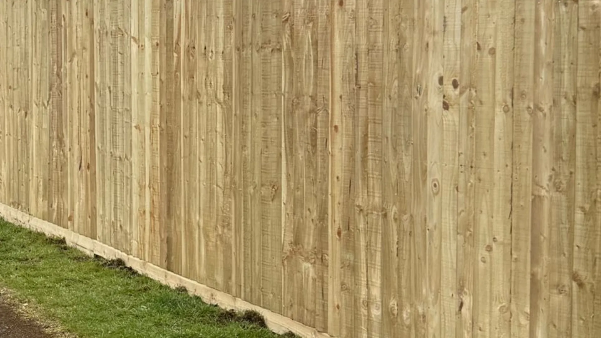 Long run of newly installed timber fencing beside a grass verge