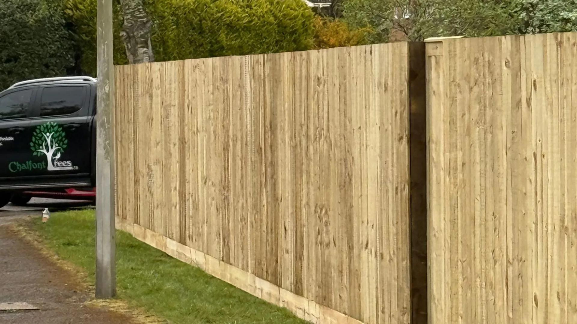 New featheredge fence panels installed along a roadside garden boundary